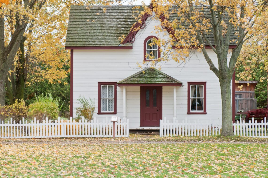 Une maison blanche avec un arbre sur le côté, à l'automne